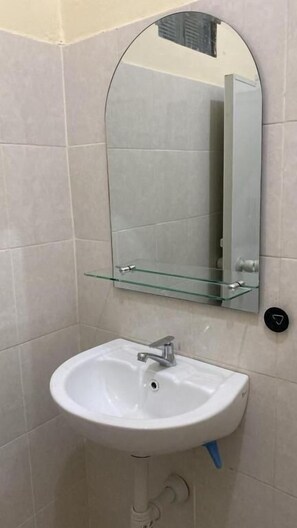 A bathroom with a white sink, a glass shelf, and a mirror. - Ndalem Tirta Yogyakarta (Yogyakarta)