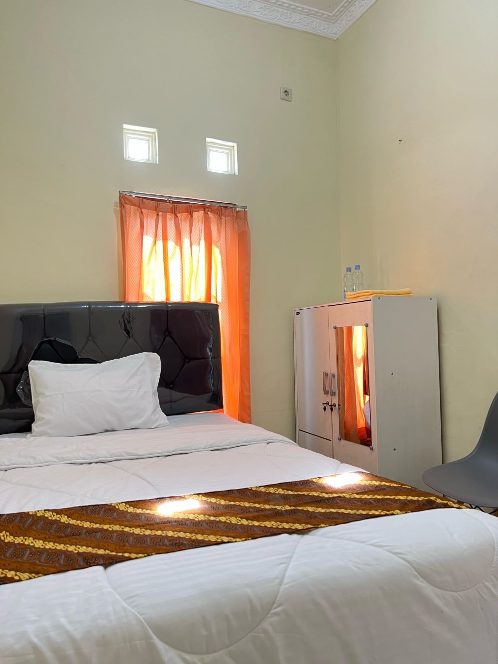 Ein Hotelzimmer mit Bett, Kleiderschrank und einem Fenster mit Vorhängen.