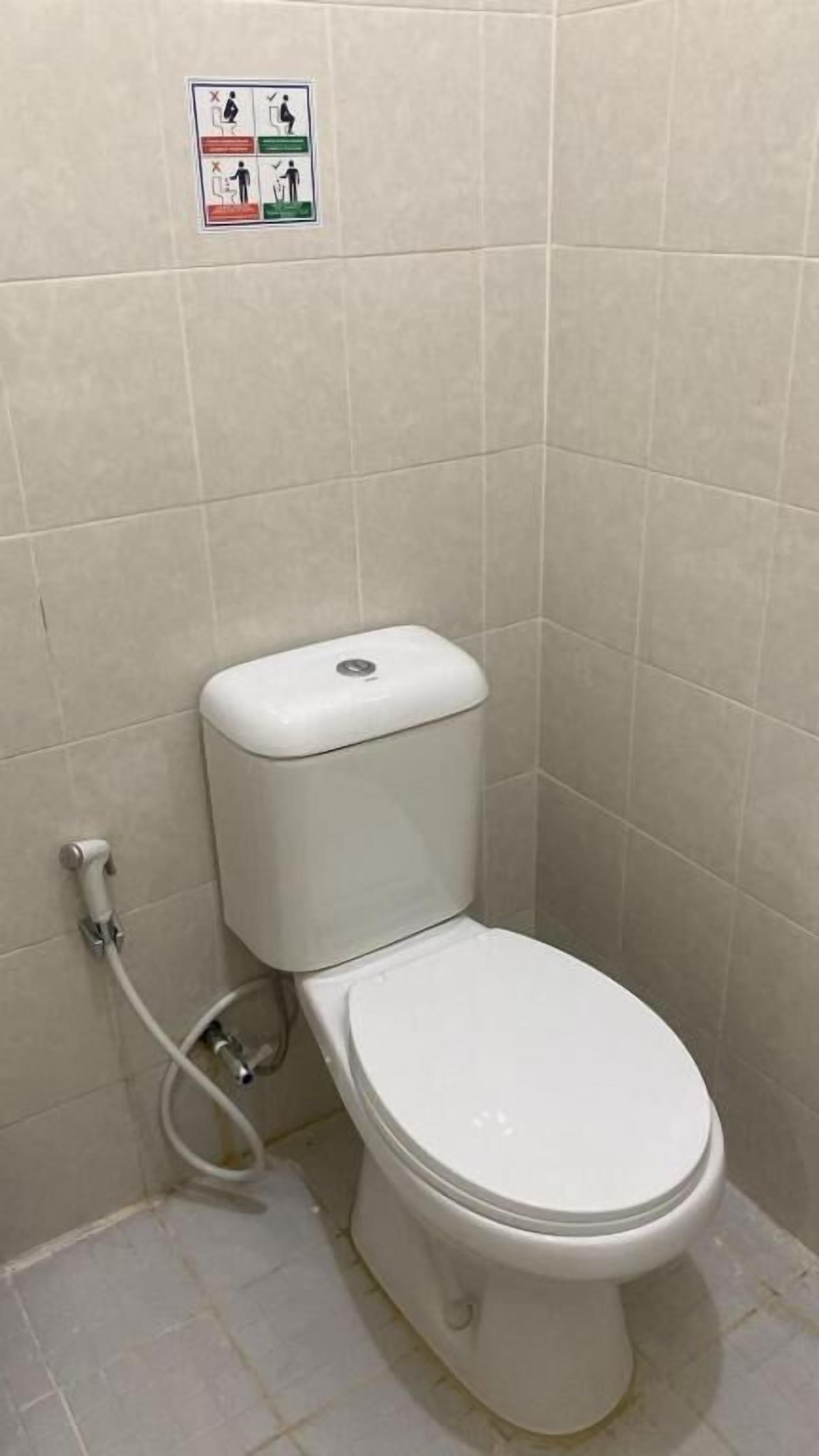 A standard toilet in a bathroom with tiled walls and floor.