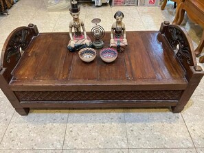 A wooden bench with two decorative figures and two bowls. - Ndalem Tirta Yogyakarta (Yogyakarta)