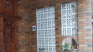 Una habitación con pared de ladrillo, un armario de madera, una separador decorativo blanco y varias plantas en macetas.