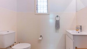 Une salle de bain avec des toilettes, un lavabo et une fenêtre.