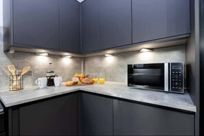 A modern kitchen with dark cabinets, a microwave, and a breakfast setup on the counter.