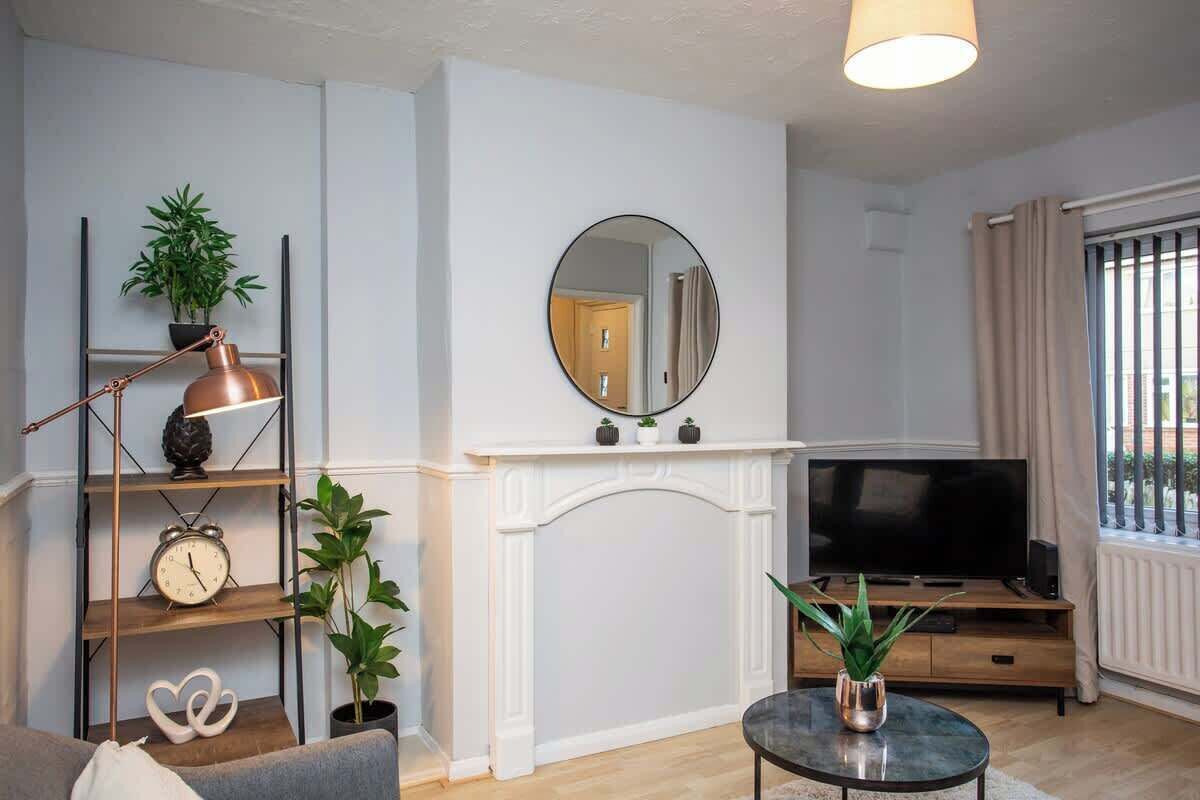 Een woonkamer met een open haard, een televisie, een salontafel en een boekenkast met decoratieve objecten.