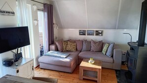 A cozy living room with a sofa, a coffee table, a TV, and a fireplace. - Cozy Holiday Home in Sint Maartenszee (Sint Maartensvlotbrug)