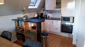 A compact kitchen with a skylight, a coffee machine, a microwave, and a built-in oven. - Cozy Holiday Home in Sint Maartenszee (Sint Maartensvlotbrug)