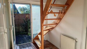 A wooden staircase leading to a second floor, a sliding glass door to a garden, and a white radiator on the floor. - Cozy Holiday Home in Sint Maartenszee (Sint Maartensvlotbrug)