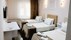 Habitación de hotel con dos camas, un escritorio, un televisor y una ventana con cortinas.