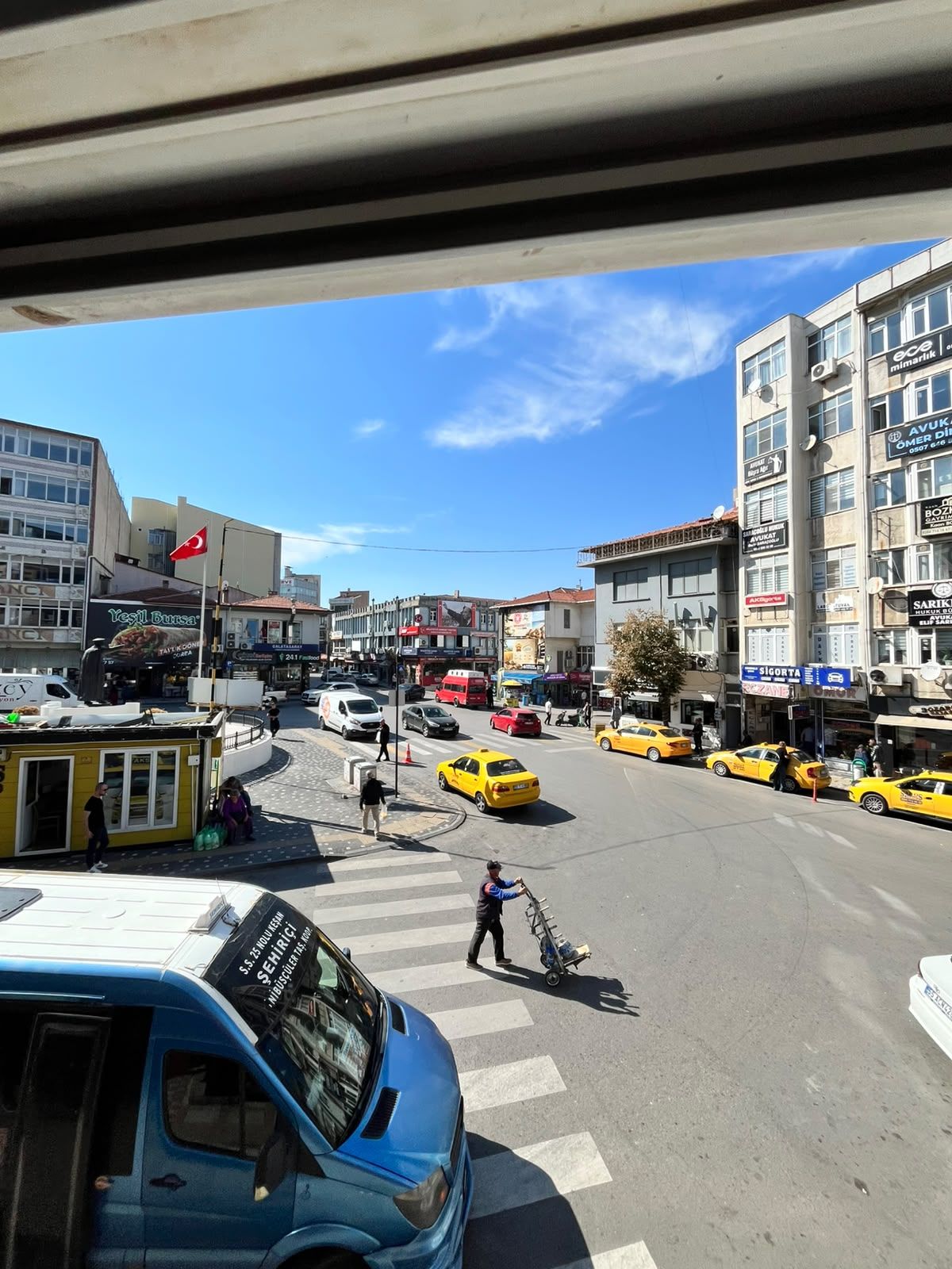 Escena urbana concurrida, con varios taxis amarillos, peatones y edificios comerciales.
