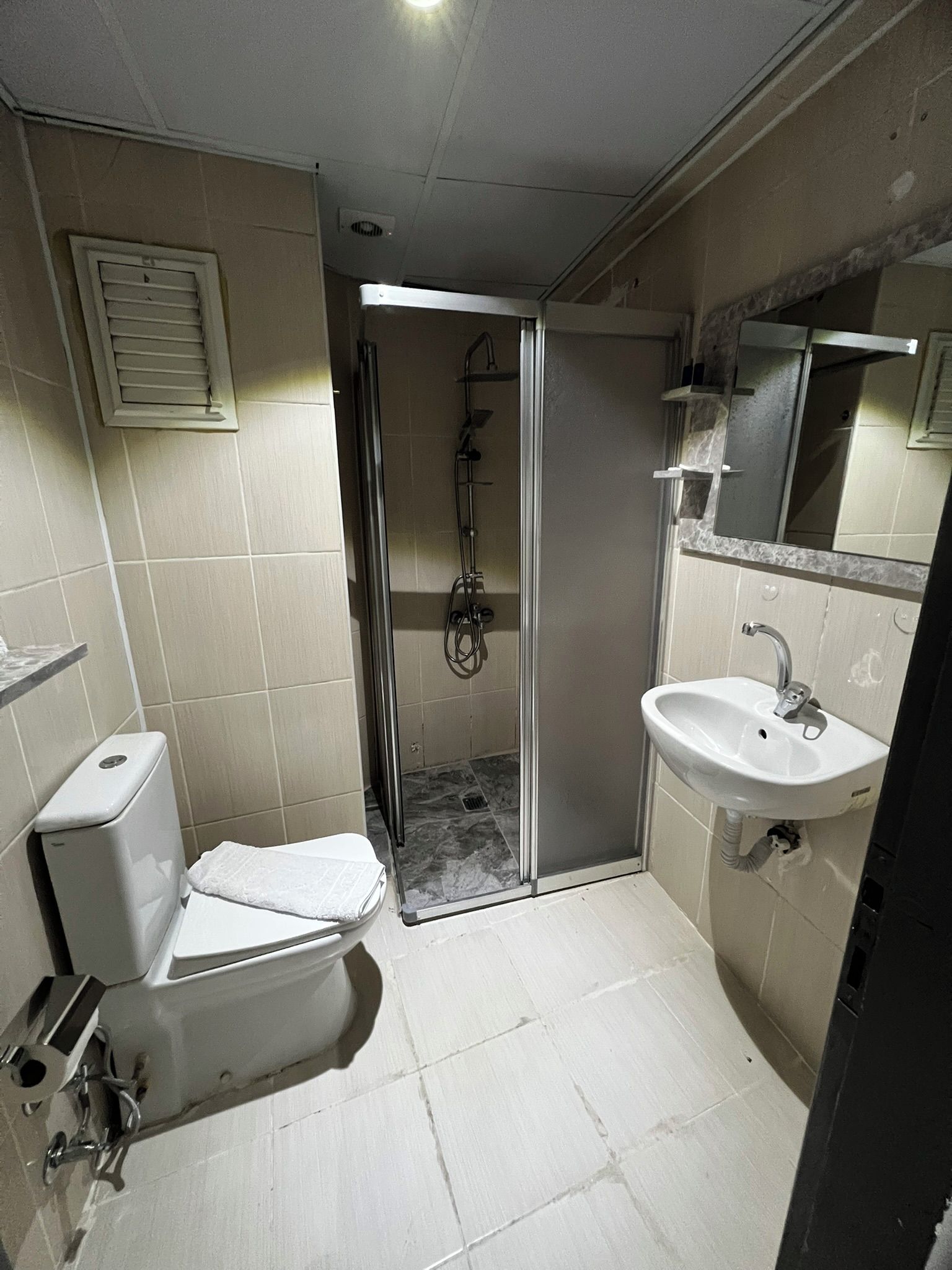 A compact bathroom with a toilet, sink, and shower.