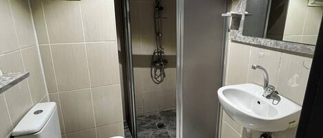 A compact bathroom with a toilet, sink, and shower.