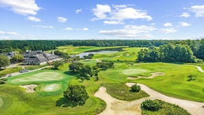 A golf course with a clubhouse, a lake, and surrounding forest. - Angie's Place w Huge Resort Pool n Hot Tub (North Myrtle Beach)