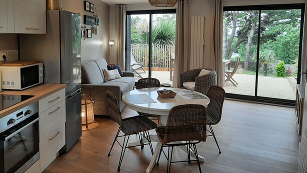 A modern kitchen with a dining area, large windows, and a view of the garden.