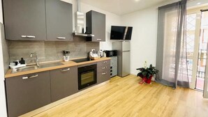 A modern kitchen with grey cabinets, a wooden countertop, a built-in oven, a microwave, and a TV mounted above the fridge. - Roman luxury location, St. Peter's  (Roma)