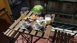 A wooden table with a potted plant, two cups of coffee, a glass of milk, and a plate with toast and jam on a balcony. - Roman luxury location, St. Peter's  (Roma)