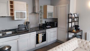 A modern kitchen with white cabinets, stainless steel appliances, and a black countertop.