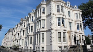 A row of white, historic buildings with large windows and a central entrance.