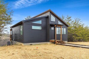 Een modern huis met twee verdiepingen, grote ramen en een houten terras.