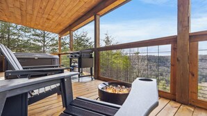 Une terrasse extérieure équipée d’un barbecue, d’un foyer et offrant une vue sur le paysage environnant.