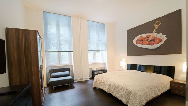 A bedroom with a bed, a dresser, a bench, and a painting on the wall.