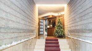 A staircase with a red carpet leading to a room with a Christmas tree.