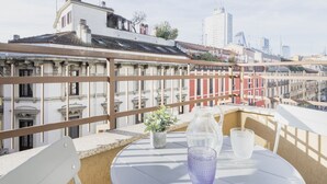A balcony with a round table, a potted plant, and a glass of water.