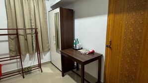 Una habitación con cama, escritorio, armario y puerta.