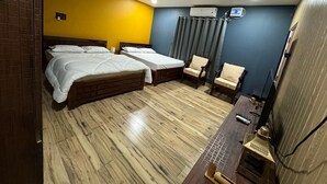 Habitación de hotel con dos camas, un escritorio con computadora, una silla y un equipo de aire acondicionado.