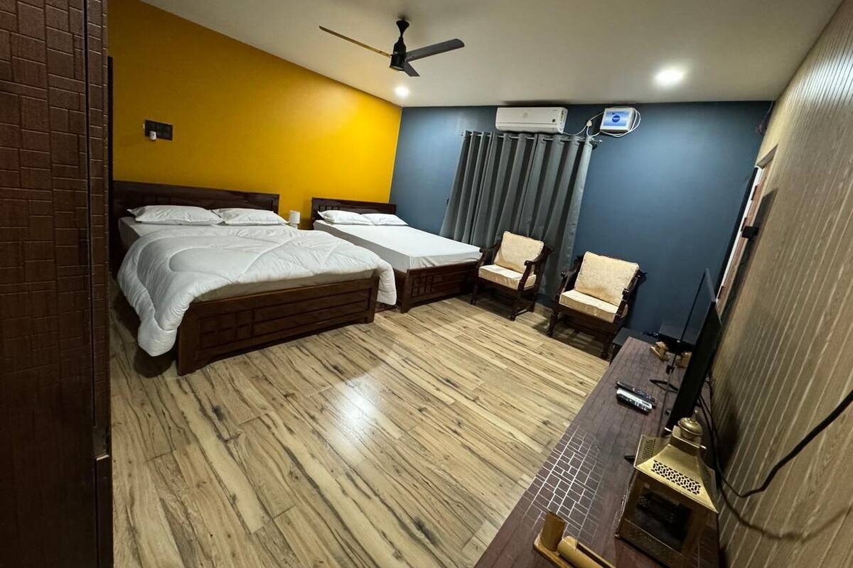 Une chambre d’hôtel avec deux lits, un bureau équipé d’un ordinateur, une chaise et un appareil de climatisation.