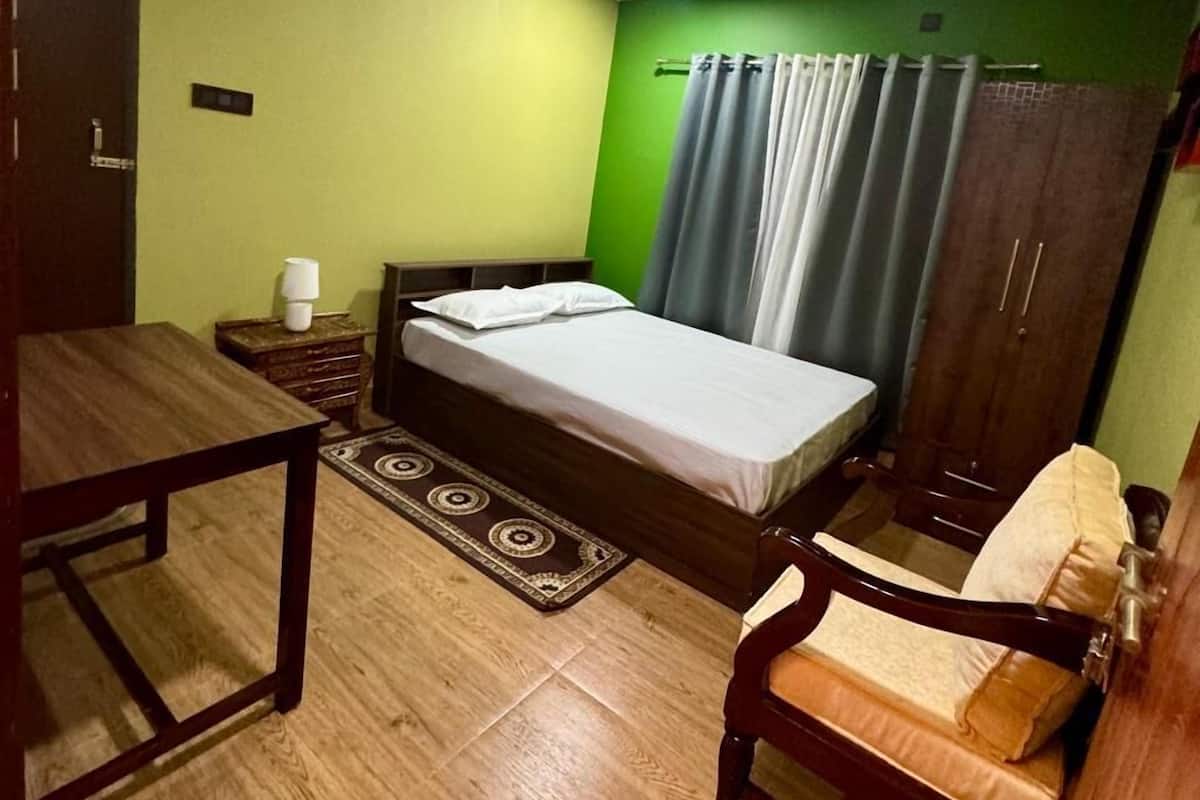 Une chambre à coucher comprenant un lit, un bureau, une chaise, une armoire et un ventilateur de plafond.