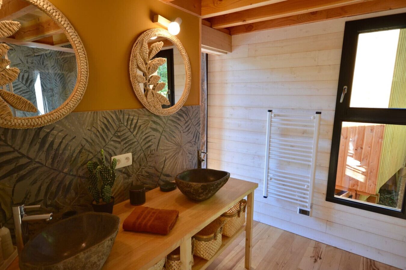 Un baño con tocador de madera, un espejo grande, lavabo y una ventana con persianas.