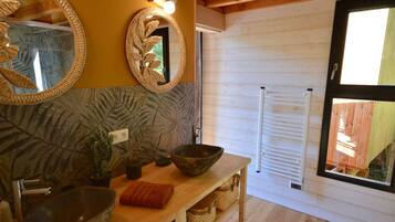 Un baño con tocador de madera, un espejo grande, lavabo y una ventana con persianas.
