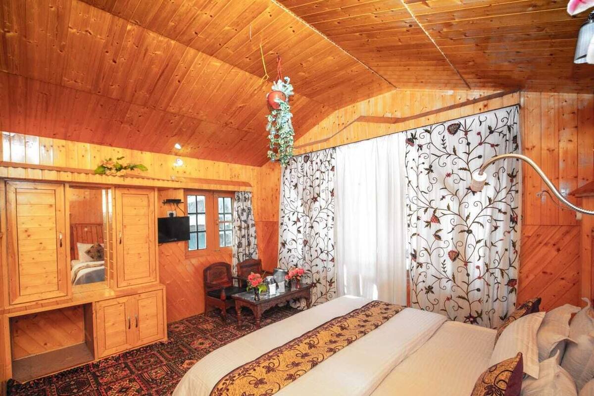 A wooden cabin bedroom with a bed, a desk, and a chair.