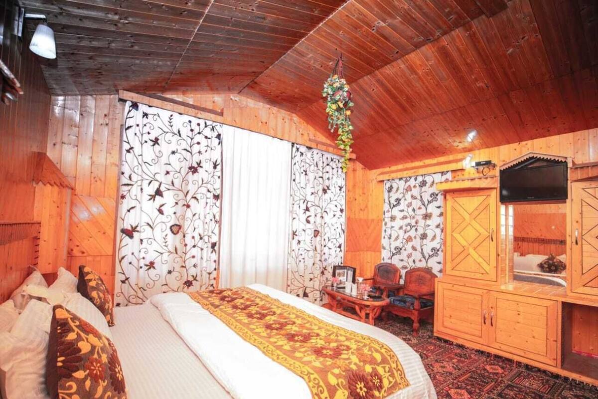 A wooden room with a bed, a desk, and a television.