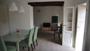 Un comedor con una mesa y sillas, un televisor y armarios al fondo.