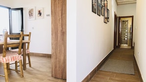 Un pasillo con suelo de madera, un pilar de madera y cuadros enmarcados en la pared.