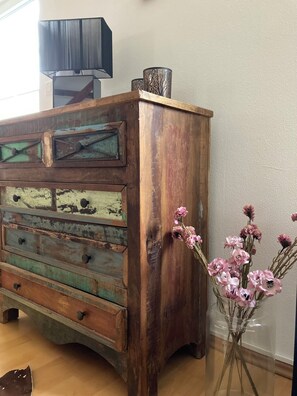 A dresser with multiple drawers and a decorative top sits in the room, accompanied by a vase with flowers.