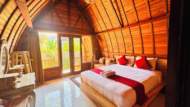 Une chambre spacieuse avec un grand lit, un plafond en bois et une vue sur l’extérieur.