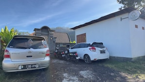 Une Grand Livina argentée et une Yaris blanche étaient garées devant un immeuble sur lequel on pouvait lire l’inscription « Volcano Valley ».