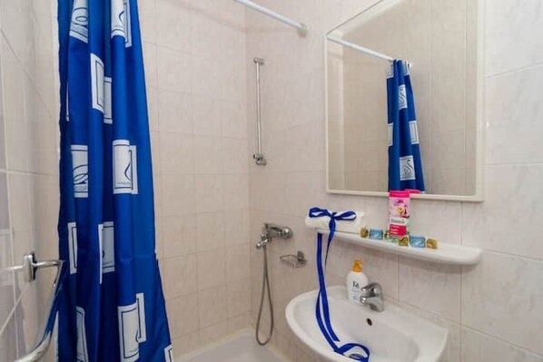Un baño con ducha, lavamanos y espejo.