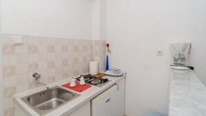 A small kitchen with a sink, a stove, and a coffee maker.