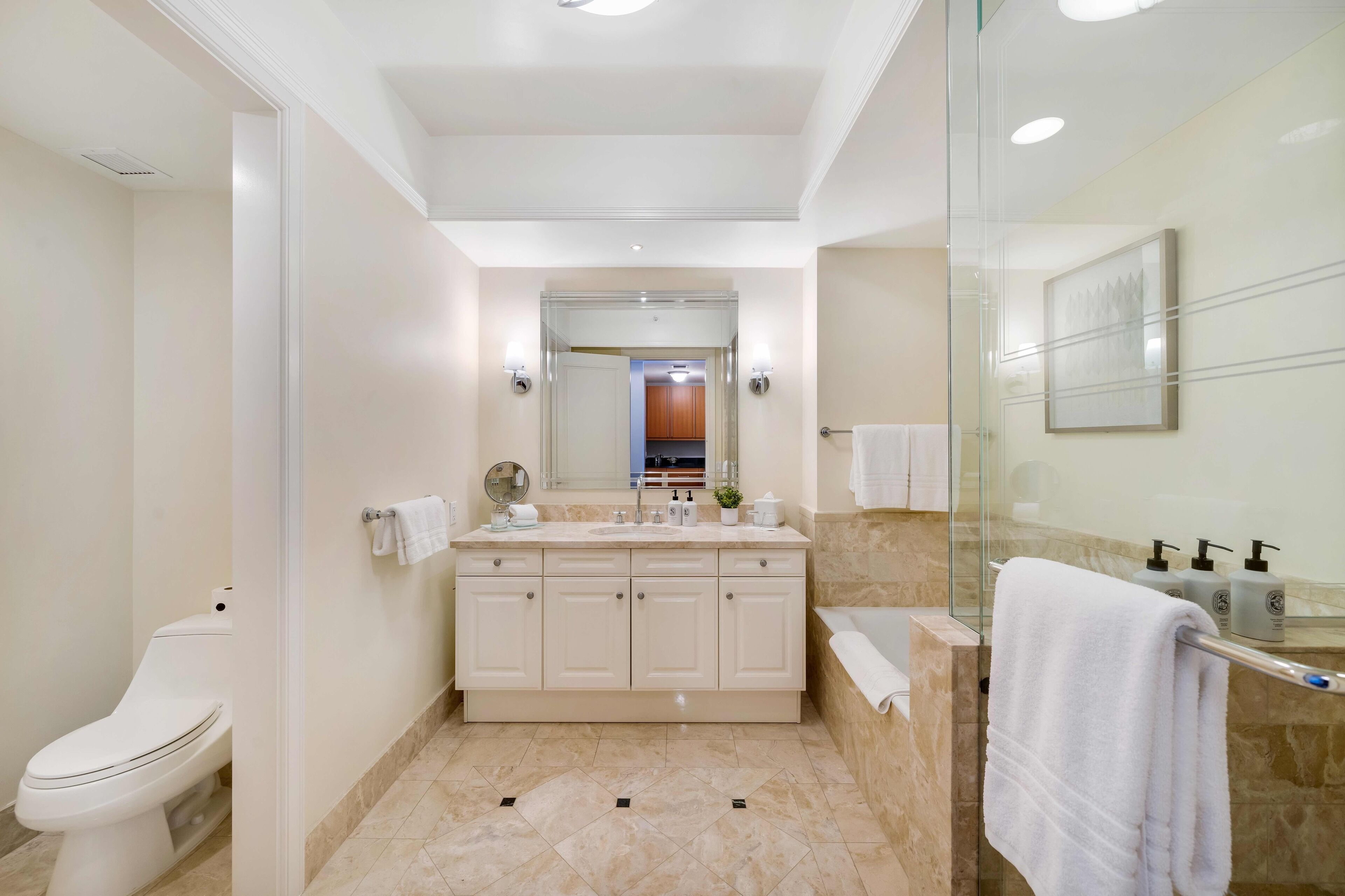A modern bathroom with a large vanity, a glass shower enclosure, and a toilet.