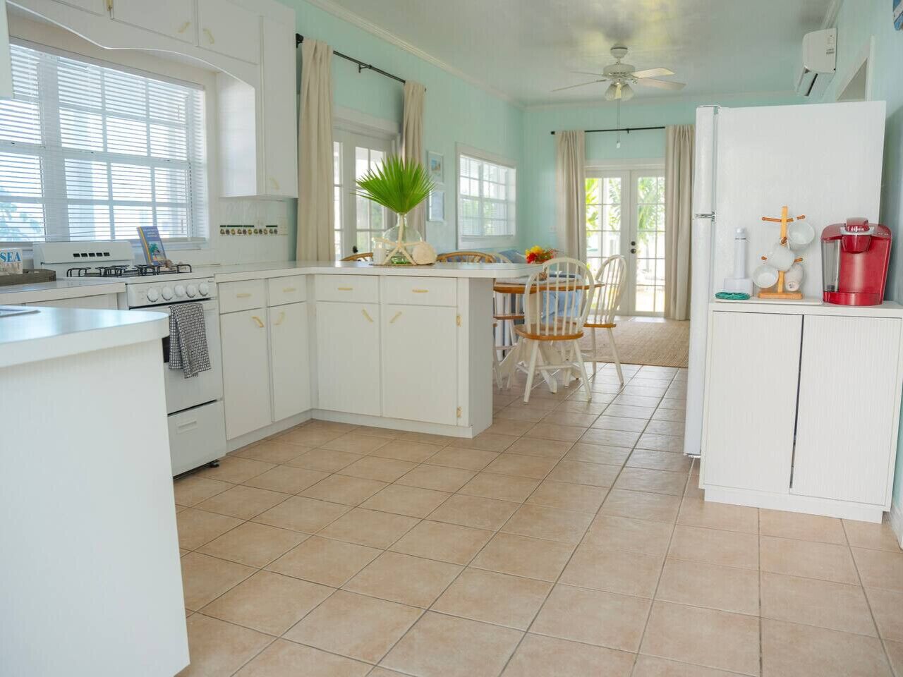 A kitchen with white cabinets, a dining table with chairs, and a refrigerator.