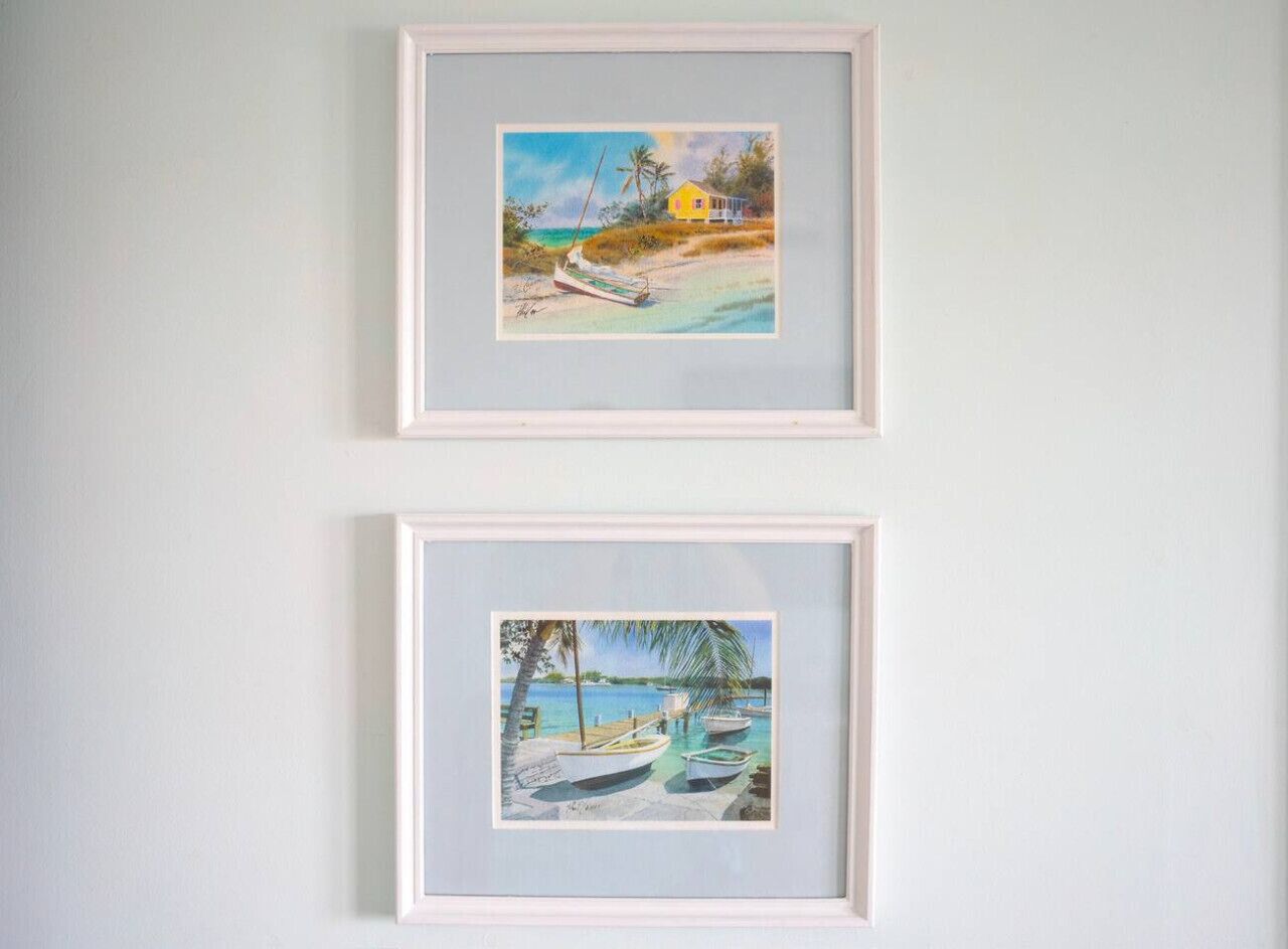 Two framed paintings of beach scenes.