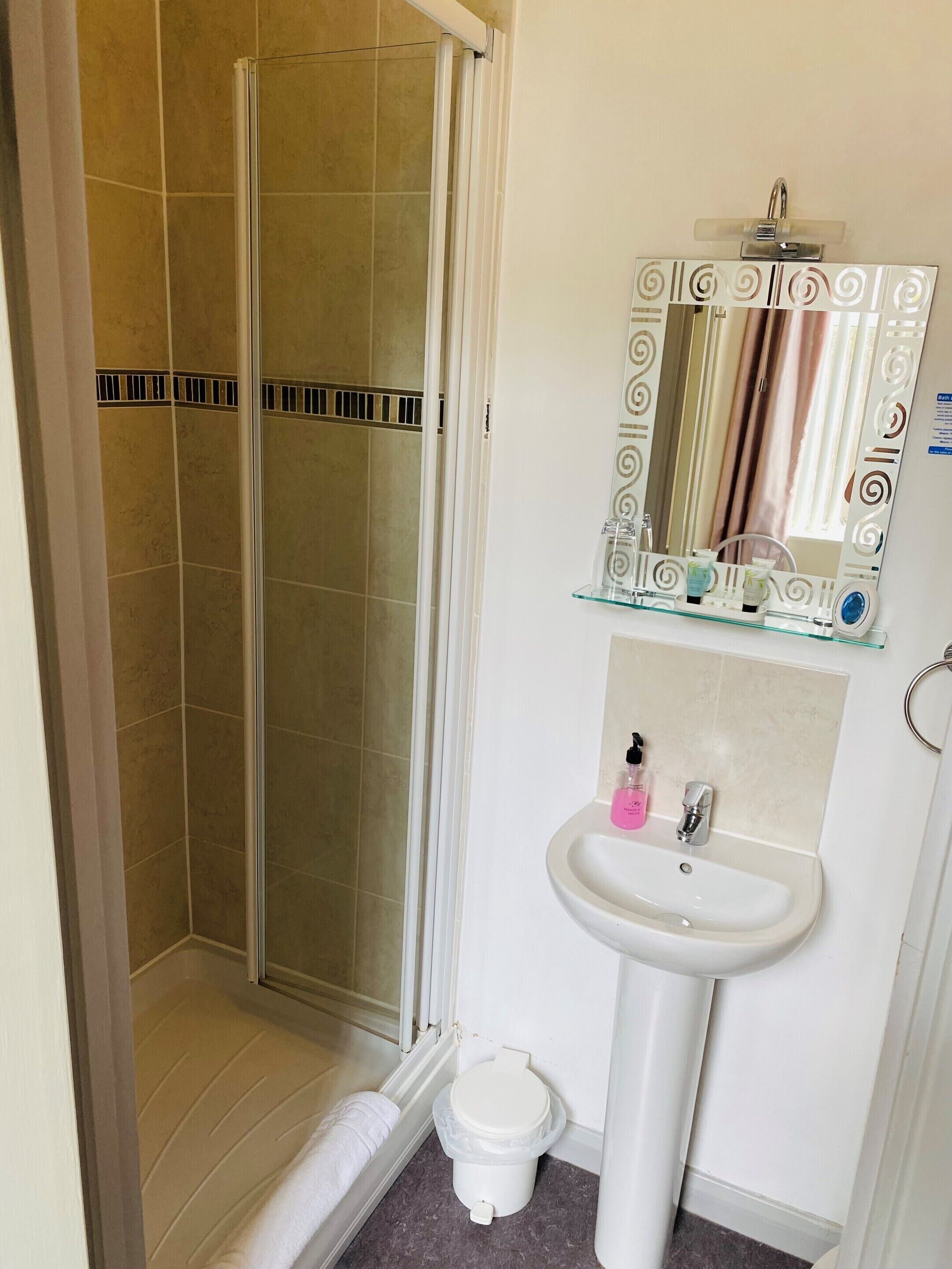 Un baño con cabina de ducha de vidrio, un lavabo con espejo y un inodoro.