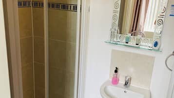 Un baño con cabina de ducha de vidrio, un lavabo con espejo y un inodoro.