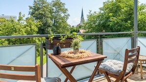 A balcony with a table, chairs, and potted plants. - EG M 70m2 2-Zimmer Wohnung (Freilassing)