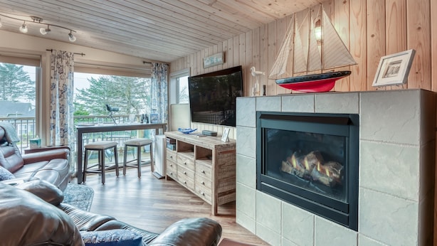 Una sala de estar acogedora con chimenea, techo de madera y un televisor grande.