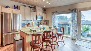 Una cocina moderna con electrodomésticos de acero inoxidable, armarios de madera y una isla grande con taburetes de bar.