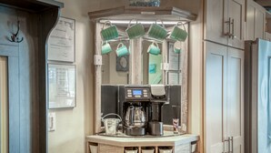 Una cocina con estación de café, que incluye cafetera, tazas y una balanza.